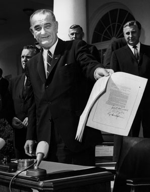 LBJ brandishes the freshly signed War on Poverty bill in 1964.