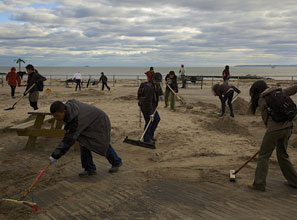 Volunteers sweep sand from the storm-battered Coney Island boardwalk.